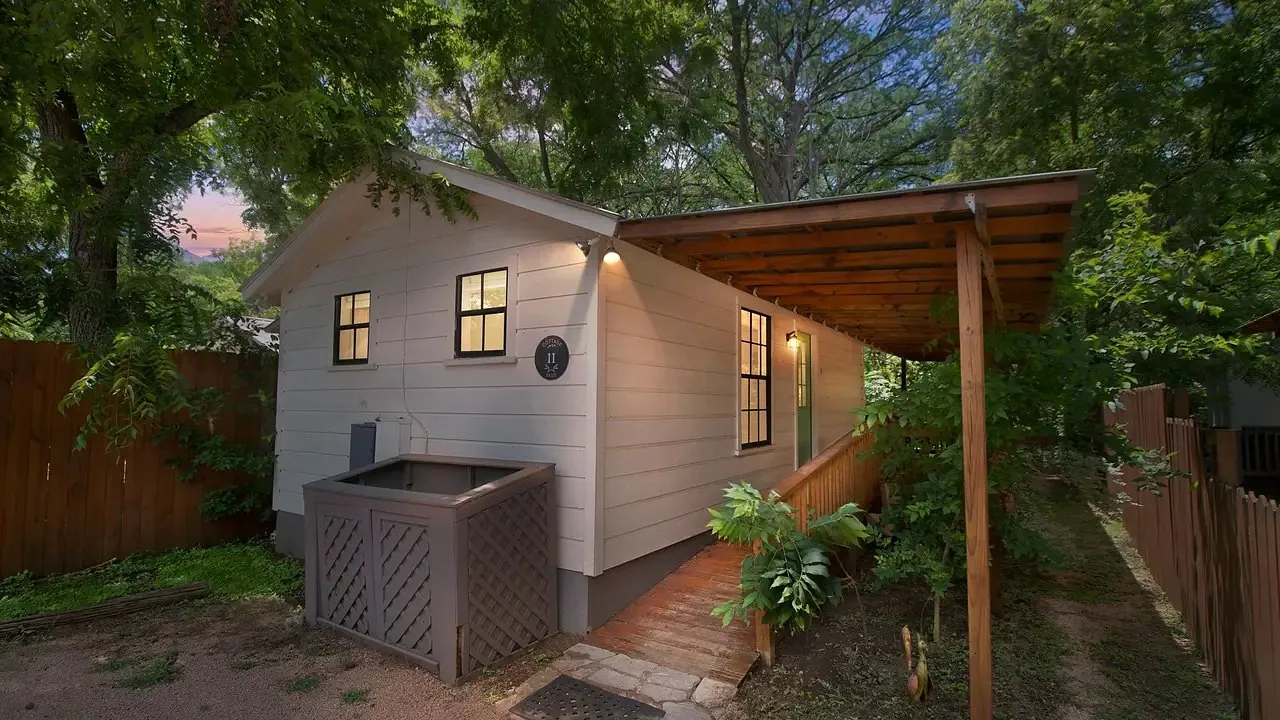 Cottage with a covered porch among trees at Cypress Creek Cottages