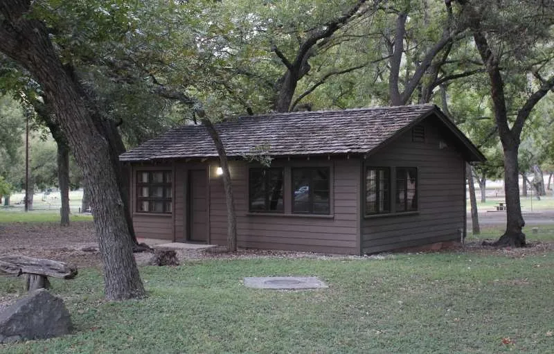 Wooden cabin with a covered porch beneath trees at Garner State Park