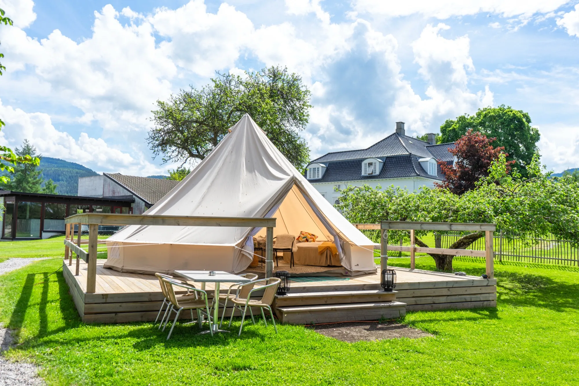 A large canvas glamping tent on a wooden platform in summer