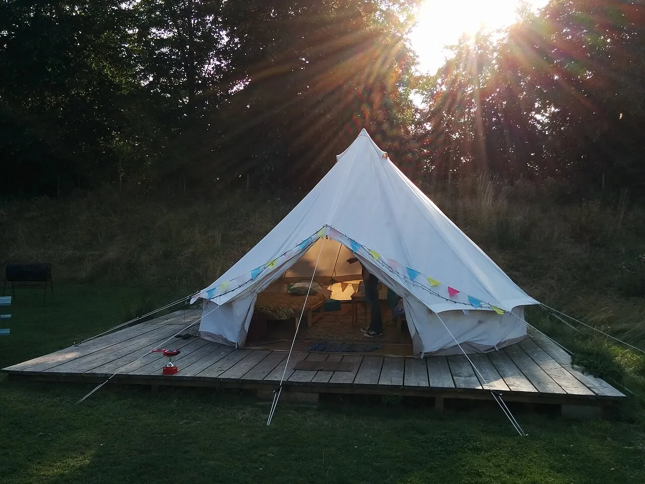 A compact wood-framed glamping hut with a canvas roof