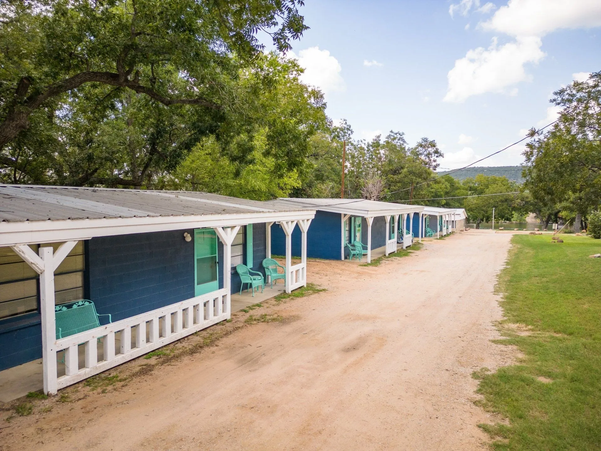 Blue cabins with white porches along a tree-shaded lane at Heart of Texas Lake Resort