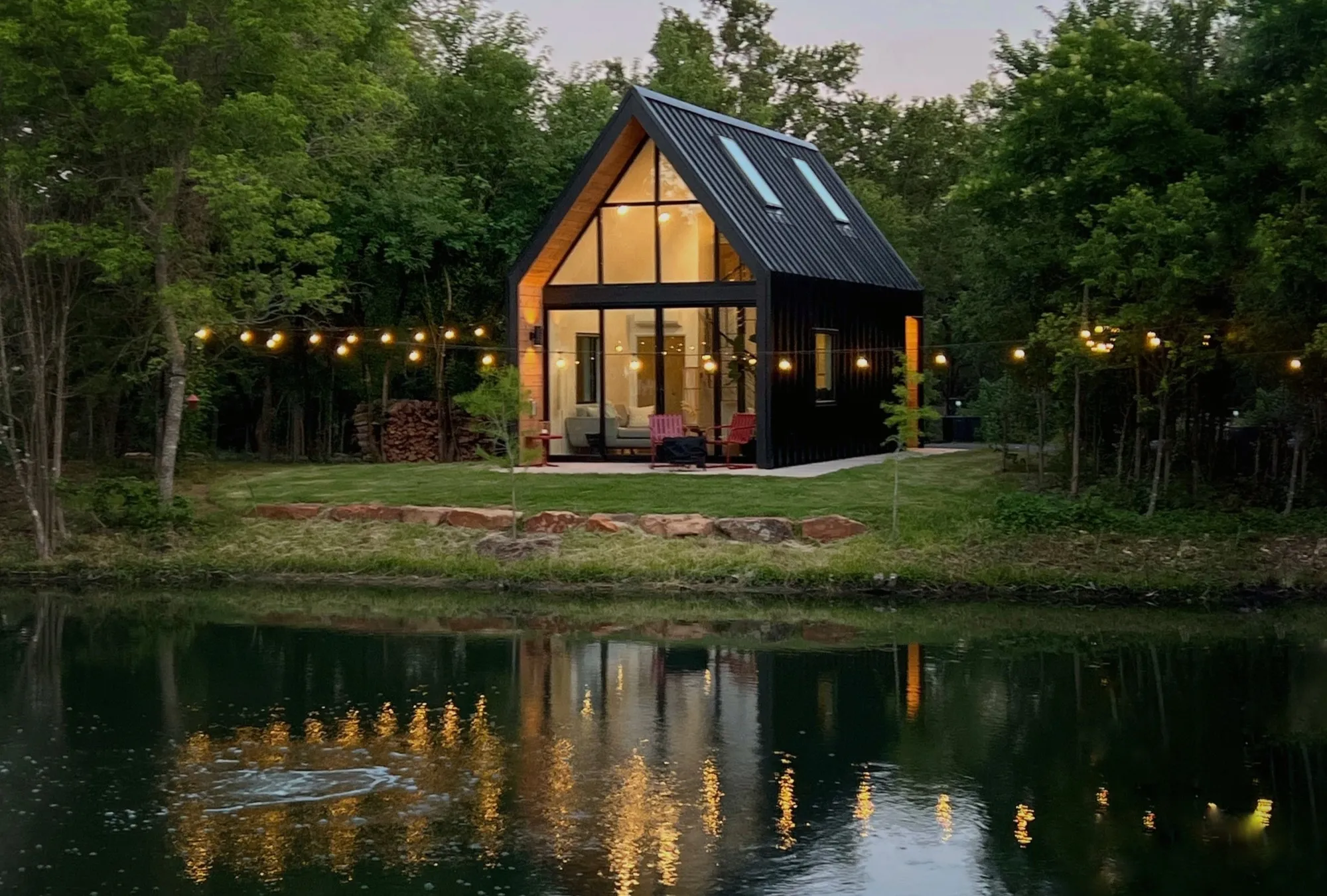 Lit A-frame cabin beside a tree-lined pond at Live Oak Lake