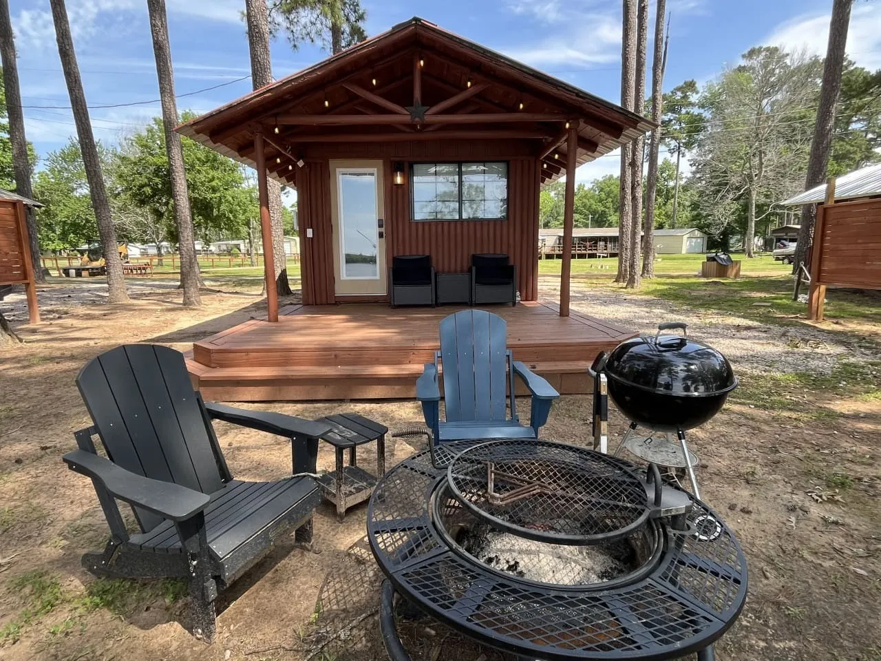 Covered cabin porch with chairs and a fire pit at Mid Lake Campground