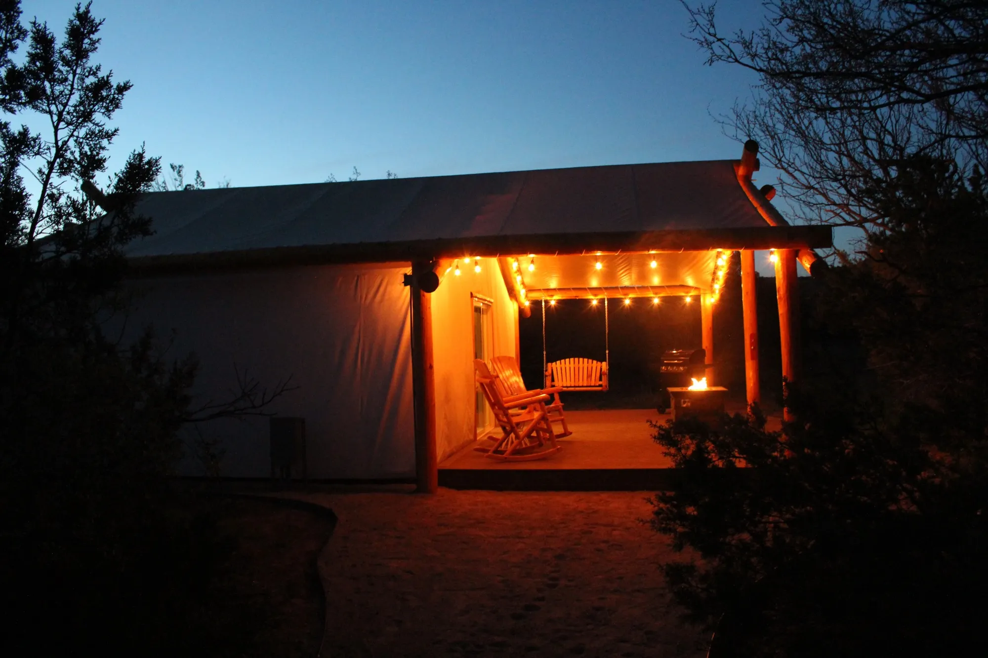 Warm light on the porch of a Palo Duro Glamping cabin at dusk