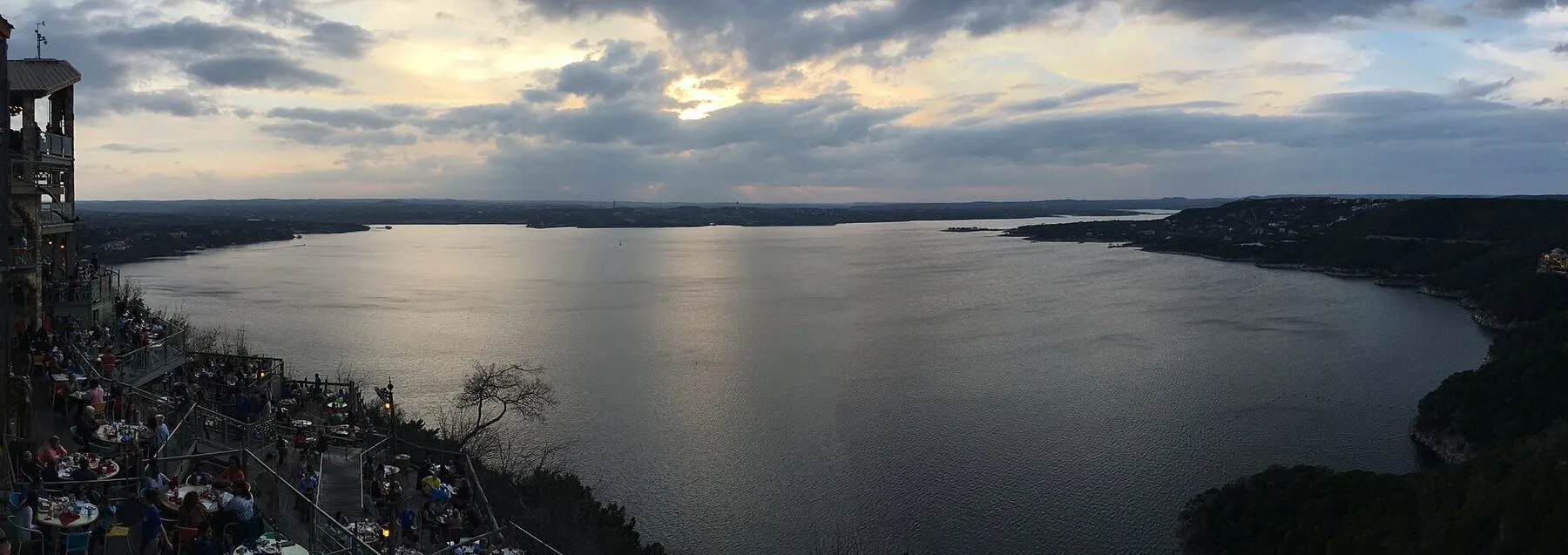 Blue Lake Travis water bordered by limestone shoreline and green hills