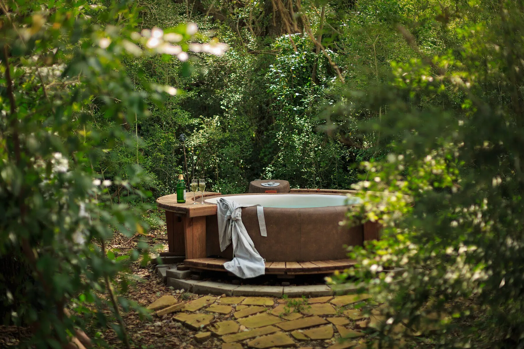 An outdoor hot tub at BlissWood's Writer's Cabin surrounded by trees