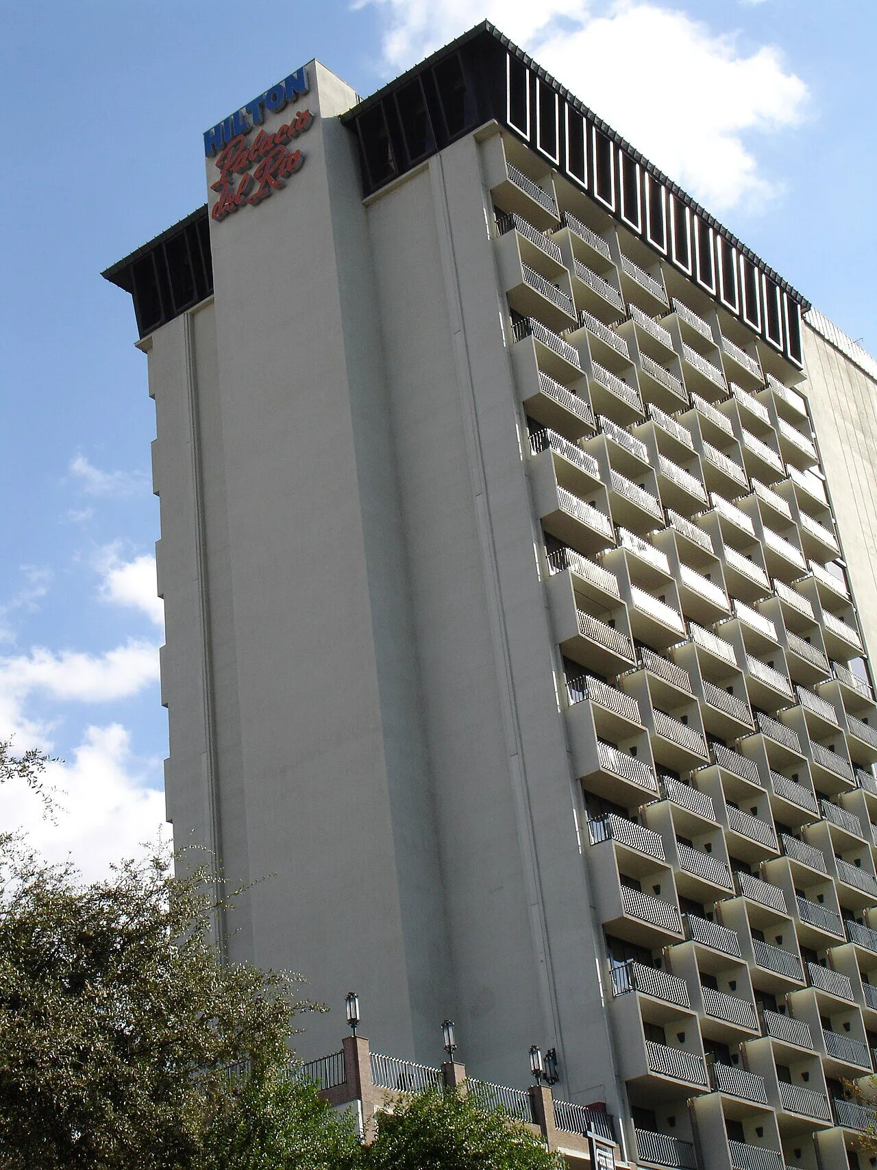 The Hilton Palacio del Rio tower rising above the River Walk with stacked balconies across its facade
