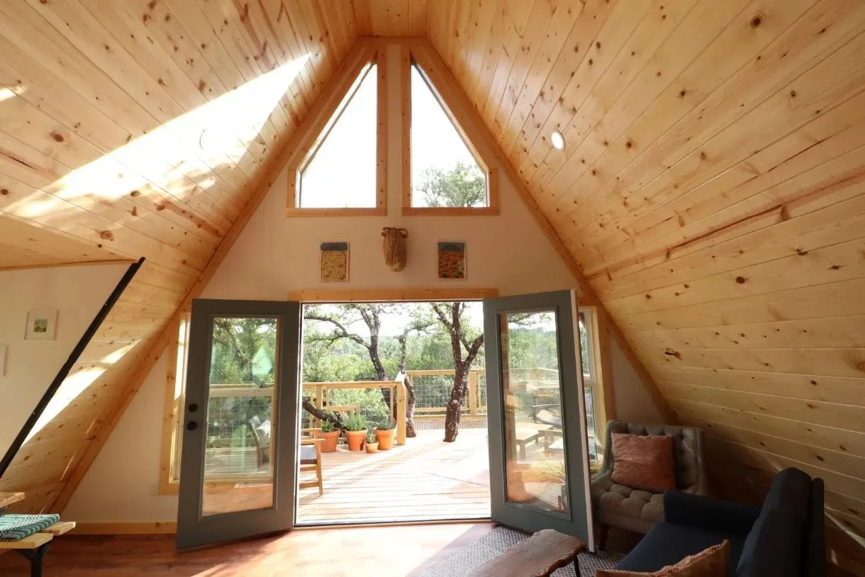 Wooden A-frame interior and open deck doors at Skybox Cabins' Hive