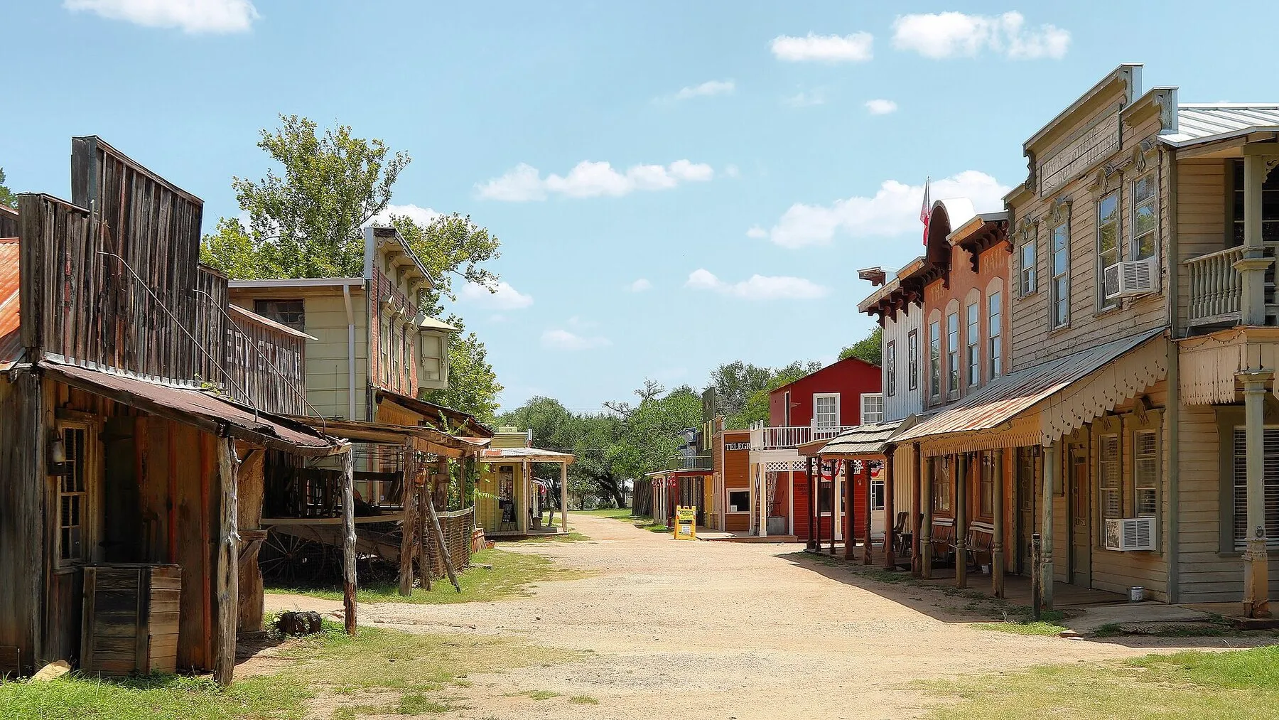 Wooden frontier-style storefronts along the replica street at Pioneer Town in Wimberley
