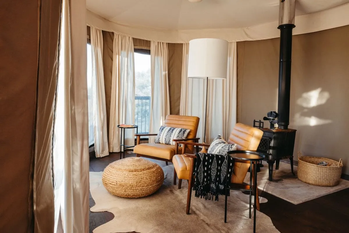 Seating area and bed inside a safari tent at Walden Retreats