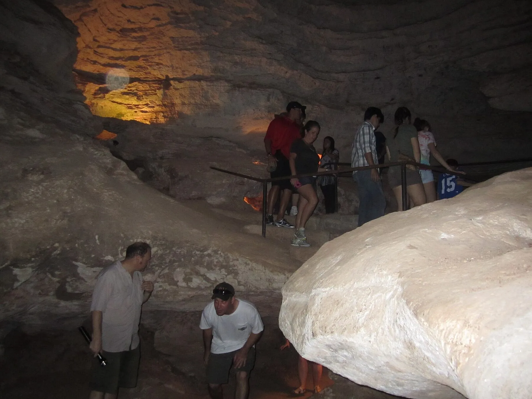 Tour visitors walk through a broad limestone passage inside Longhorn Cavern