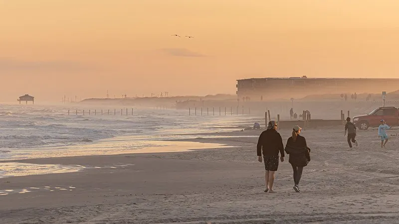 People walking along Whitecap Beach in the evening