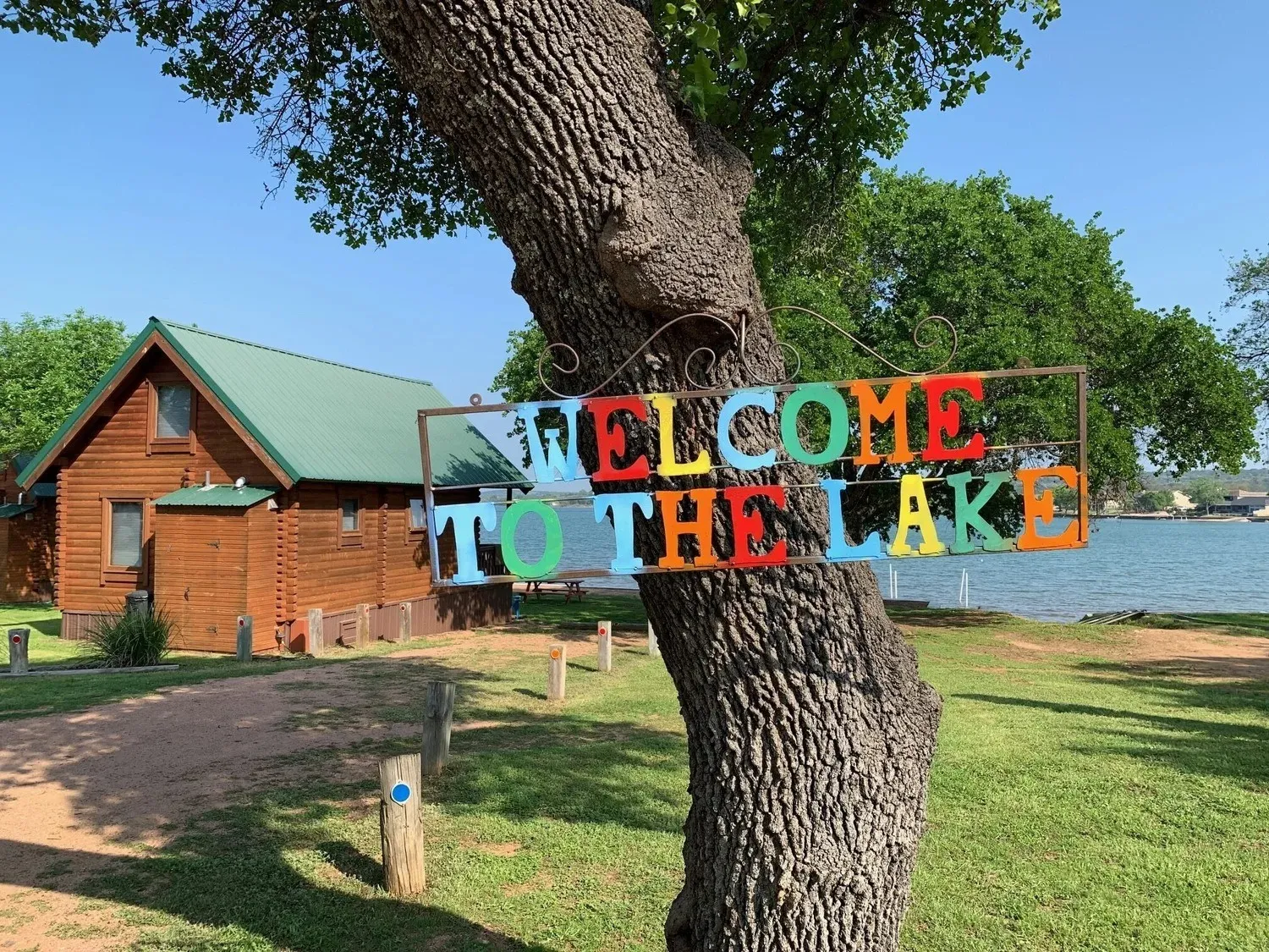 Cabin and colorful lake welcome sign at Willow Point Resort